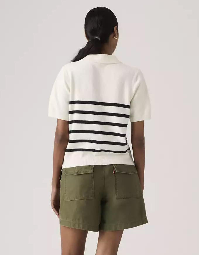 Woman wearing a white and black striped shirt with green pants on a light gray background. Super Soft Polo Sweater Isabella Stripes