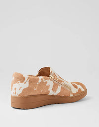 Tan and white patterned slip-on shoe on a light gray background