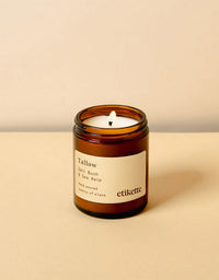 Candle in an amber jar with a white label on a beige background