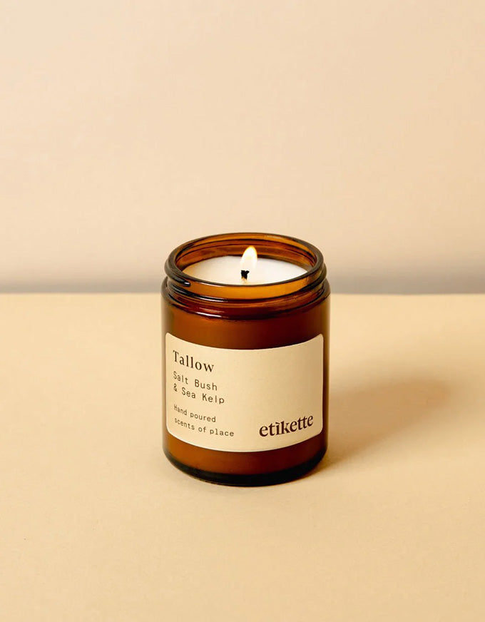 Candle in an amber jar with a white label on a beige background