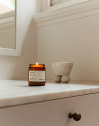 Candle in a glass jar on a marble surface with a neutral background