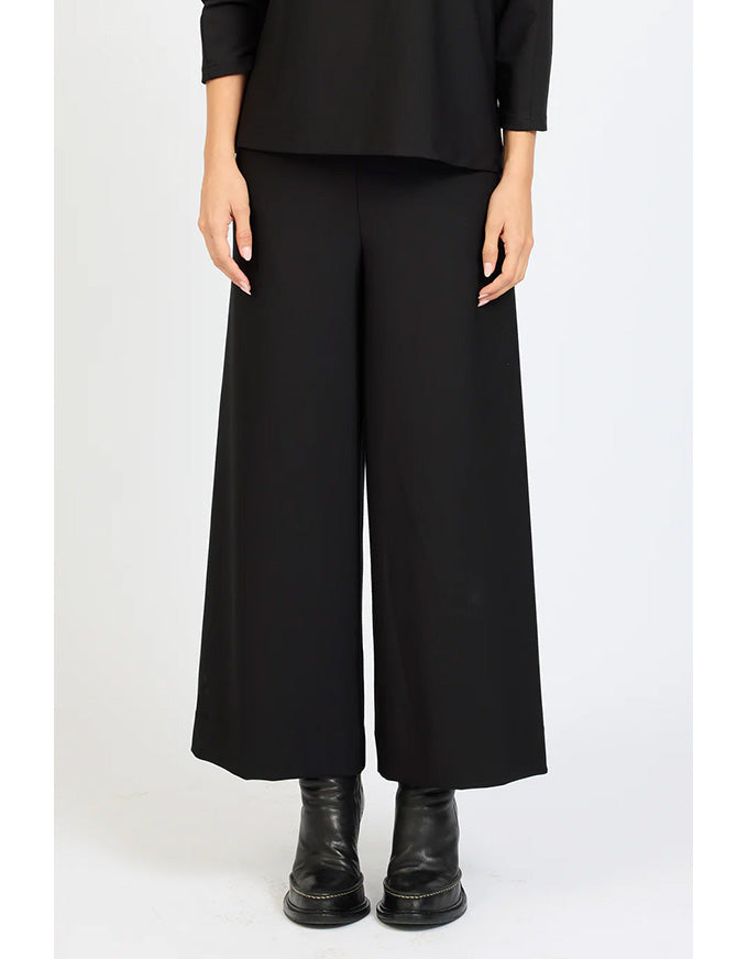 Person wearing a black outfit with wide-leg pants on a white background