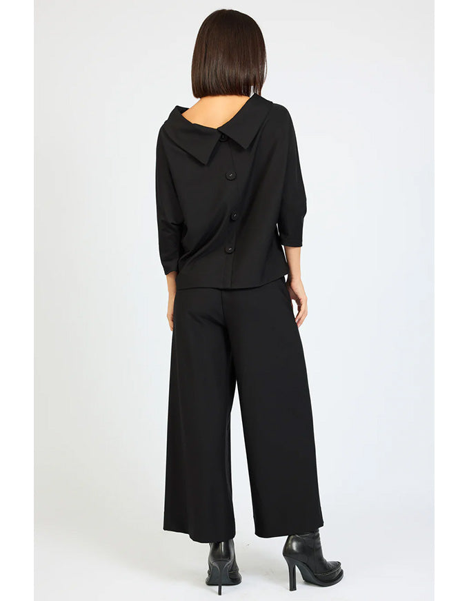 Person wearing a black outfit with wide-leg pants on a white background