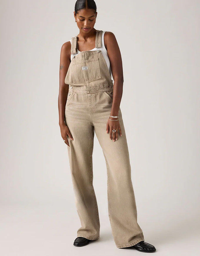 Woman wearing beige overalls on a white background