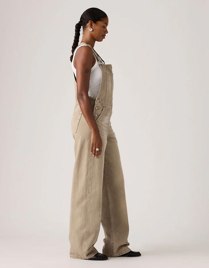 Woman wearing beige overalls on a white background