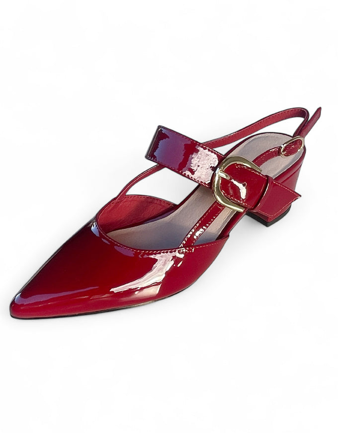 Red patent leather shoe with a gold buckle on a white background