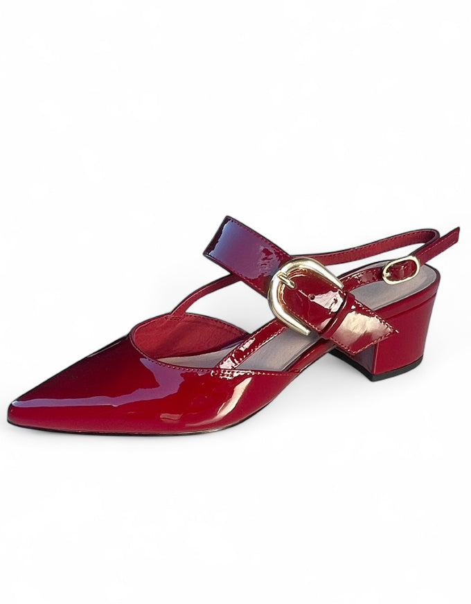 Red patent leather shoe with a gold buckle on a white background