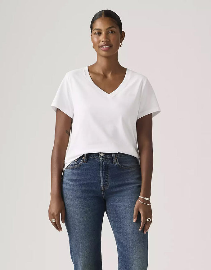 Woman wearing a white t-shirt and blue jeans against a plain background