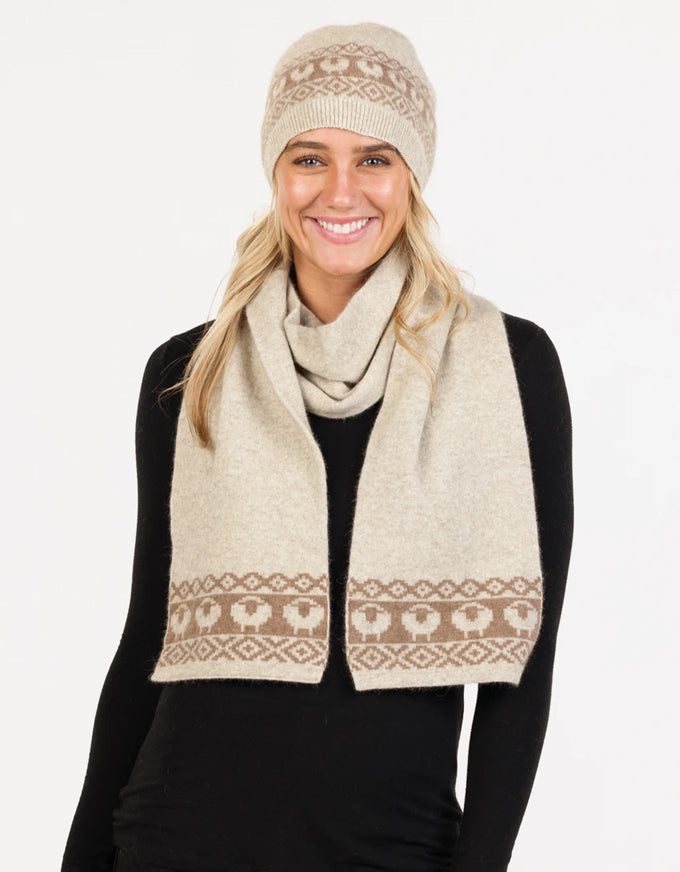 Woman wearing a beige patterned scarf and beanie on a white background