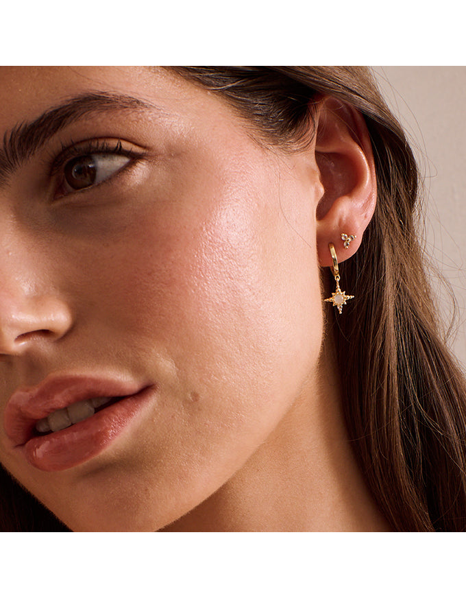 Close-up of a woman wearing gold star-shaped earrings.