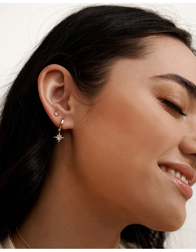 Close-up of a woman wearing a star-shaped earring with a neutral background