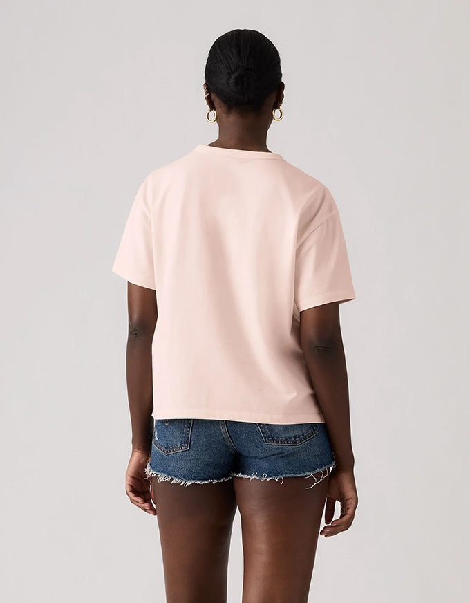 Person wearing a light pink t-shirt and denim shorts on a plain background