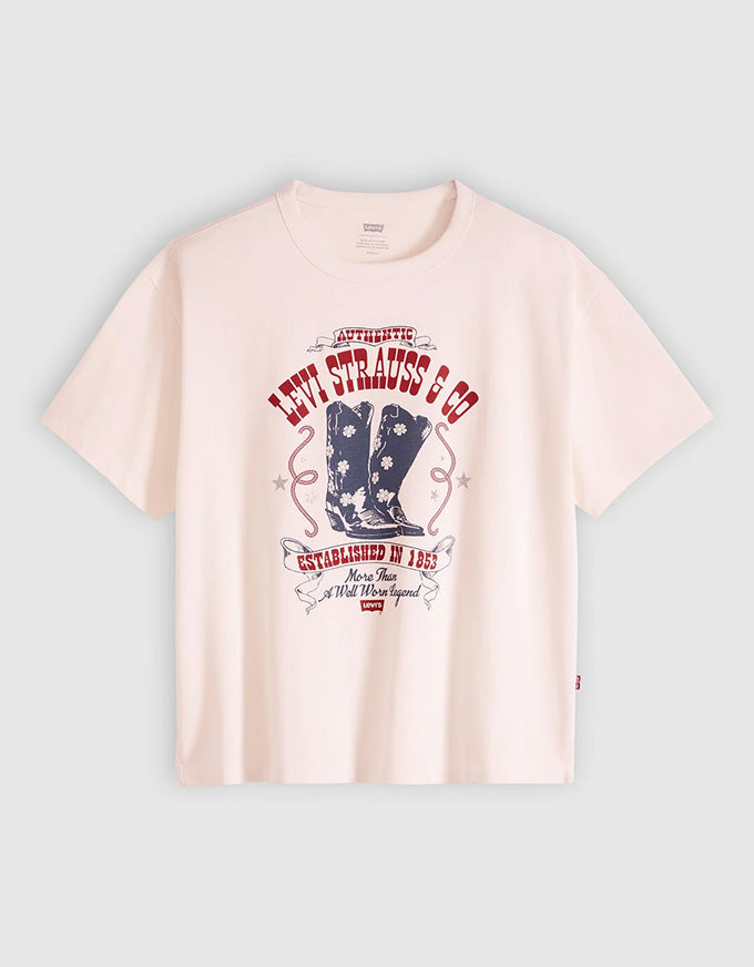 A pale pink short-sleeve t-shirt with a vintage-style graphic on the front featuring red and navy blue text and a cowboy boot illustration, displayed against a light gray background.