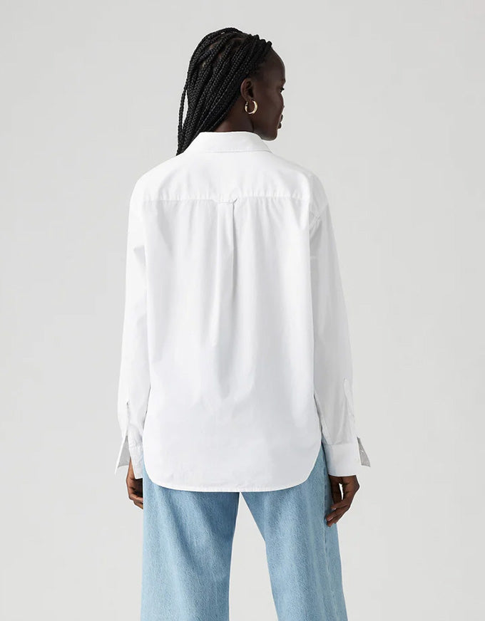 Person wearing a white shirt and light blue jeans on a plain background