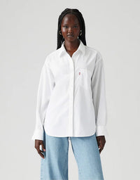 Woman wearing a white shirt with a small logo on a light gray background
