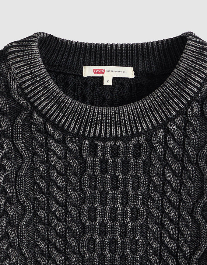 Close-up of a black and gray cable-knit crewneck sweater by Levi's, showing the textured knit pattern and the brand label inside the collar.