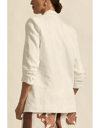 Person wearing a white blazer with a neutral background