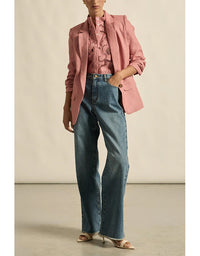 Person wearing a pink blazer and blue jeans on a neutral background