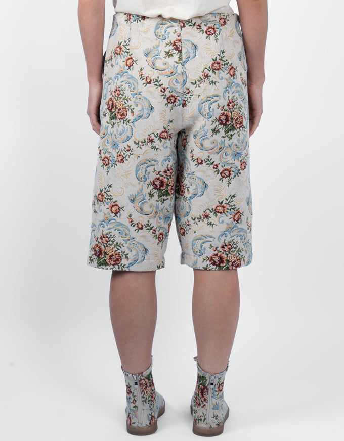 A person shown from the back wearing knee-length shorts and ankle boots with an ornate floral and scroll pattern on a light background. The product appears to be the patterned shorts, with matching boots also visible.