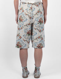 A person shown from the back wearing knee-length shorts and ankle boots with an ornate floral and scroll pattern on a light background. The product appears to be the patterned shorts, with matching boots also visible.