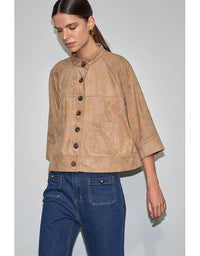 Woman wearing a beige jacket with black buttons and blue jeans on a light gray background